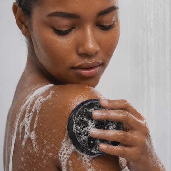 Person demonstrating the HueVine The Ingrown Hair Annihilator exfoliating bar during a shower skincare routine.